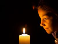 Portrait of Beautiful little girl who sitting in the dark by candle light